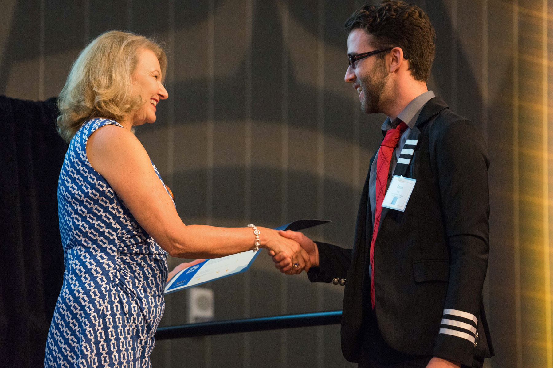 A staff member shakes the hand of a scholarship recipient. 