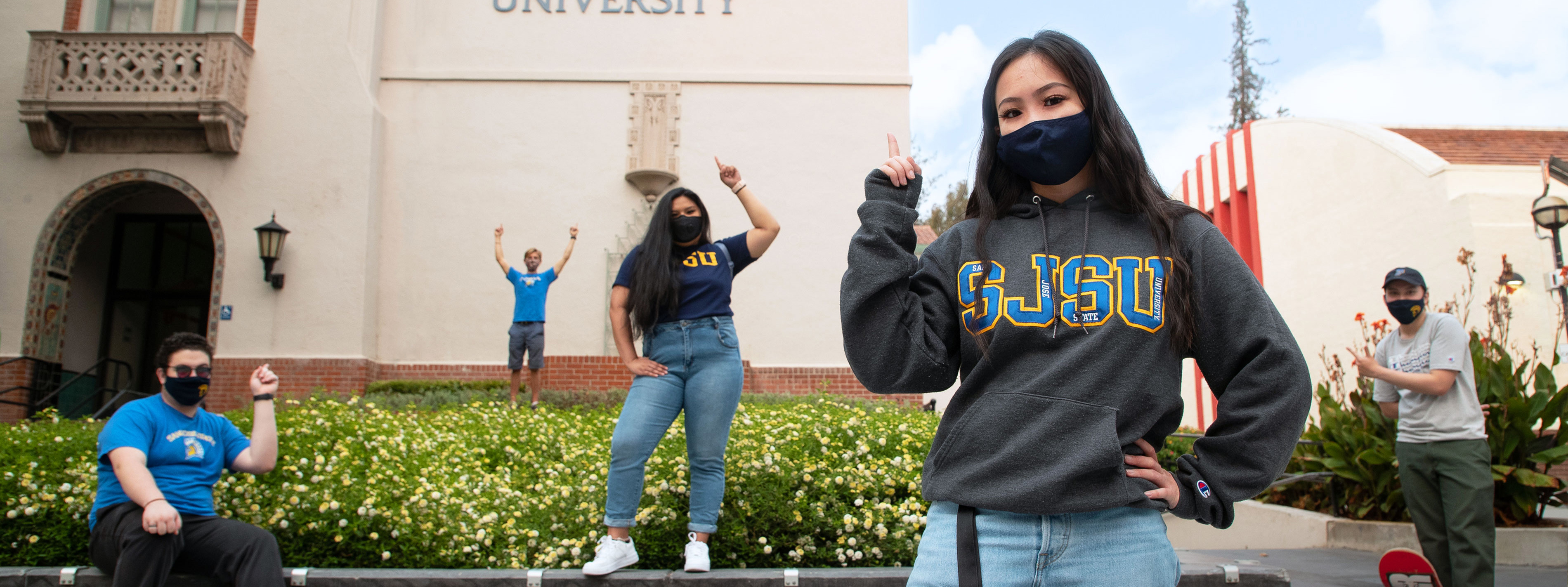 students pointing at SJSU logo