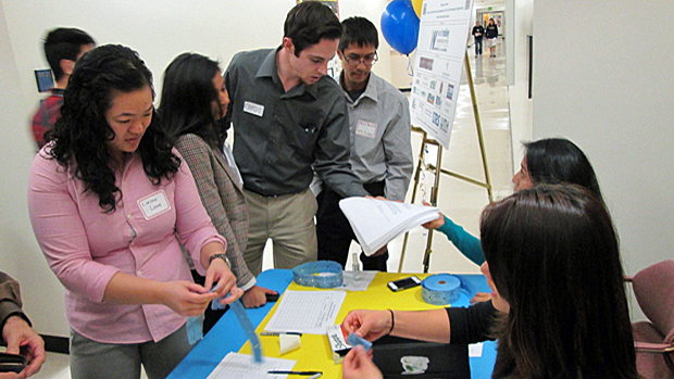 Students and faculty working together on a project around a table.