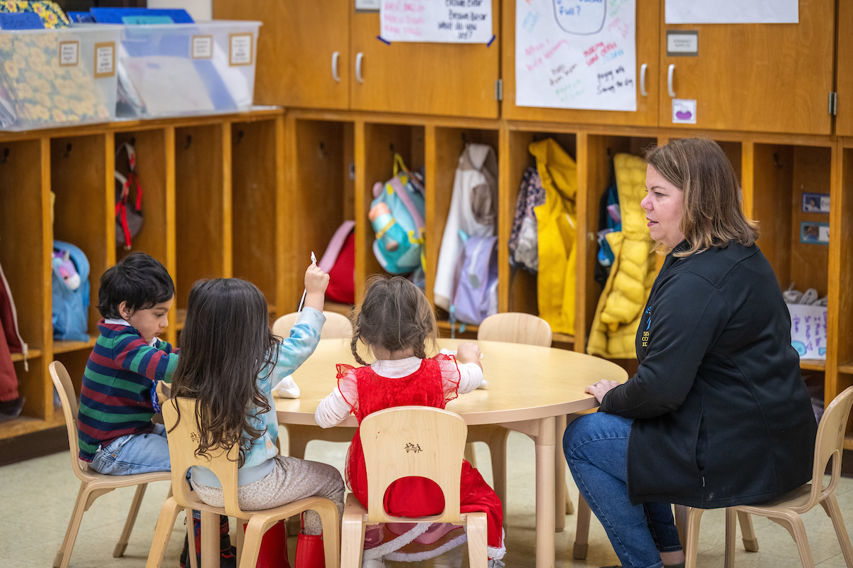 a teacher sitting with a few children students 