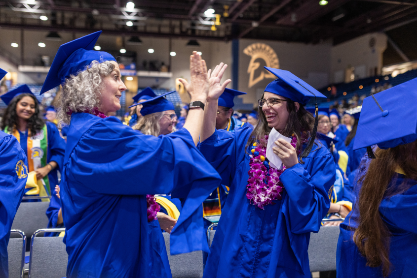 Student and faculty exchanging a high five gesture.