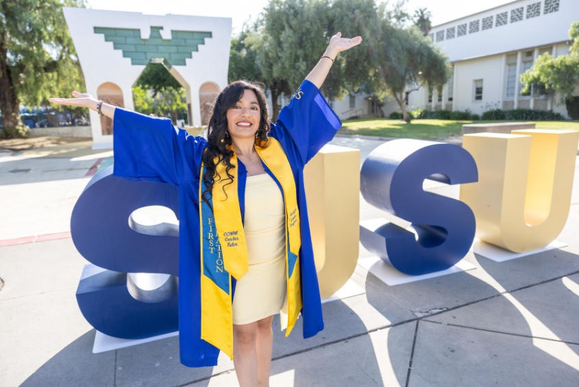 Student posing in front of SJSU letters and the Dignity Arch