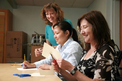 Two adults cut paper using scissors.