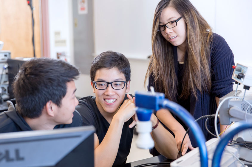 three engineering students smiling and sitting.