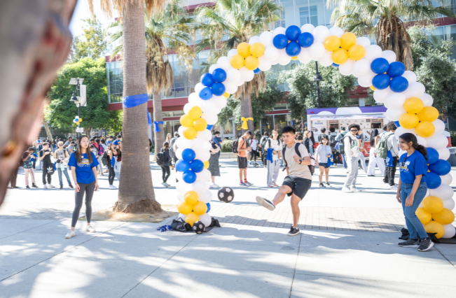 Student kicking a ball on the 7th Street Paseo during Homecoming festivities