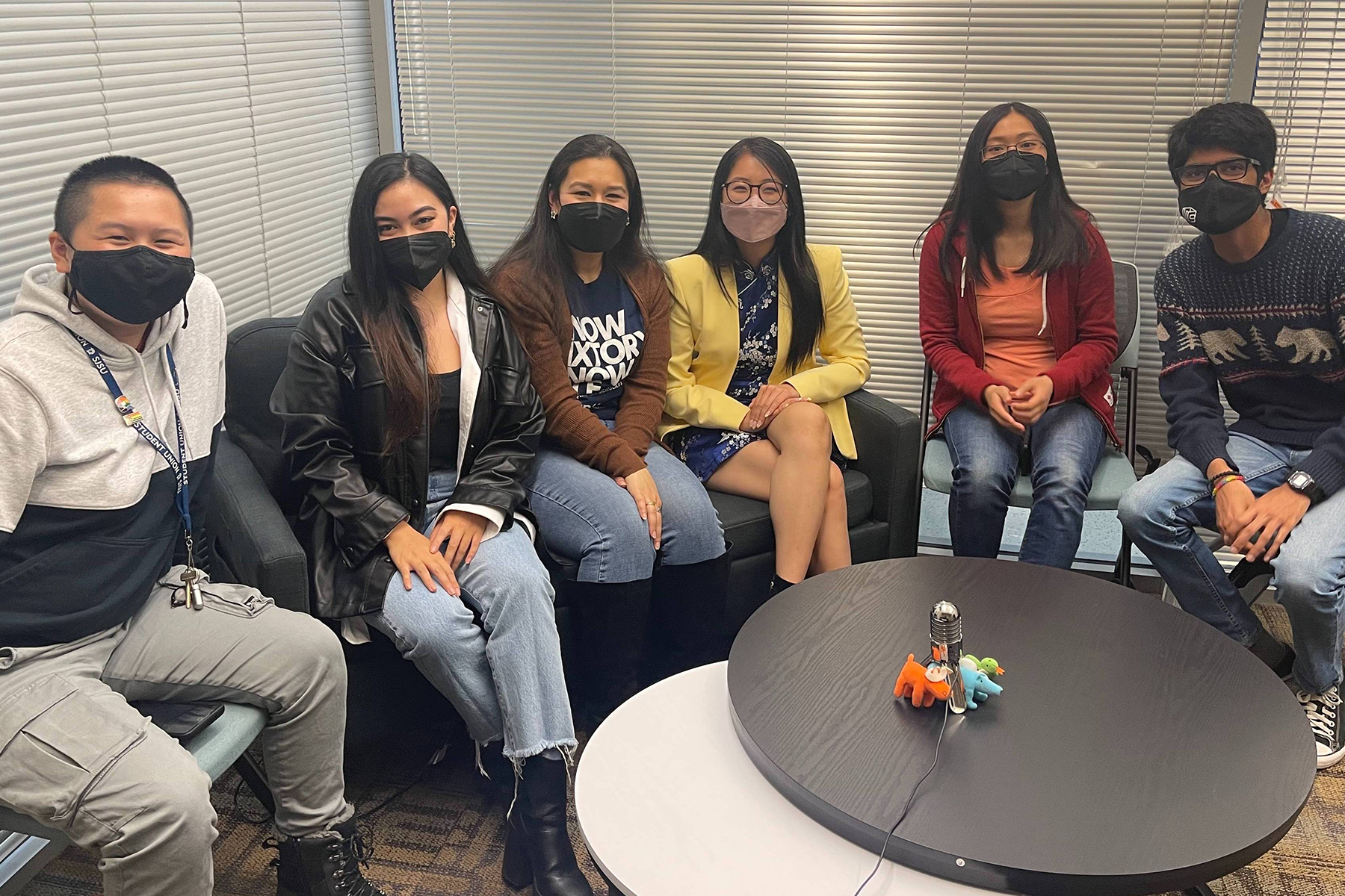 Group of students and staff sitting in a half circle on a couch and chairs.