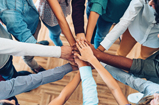 the arms of eight different people with their hands on top of each other in a circle.