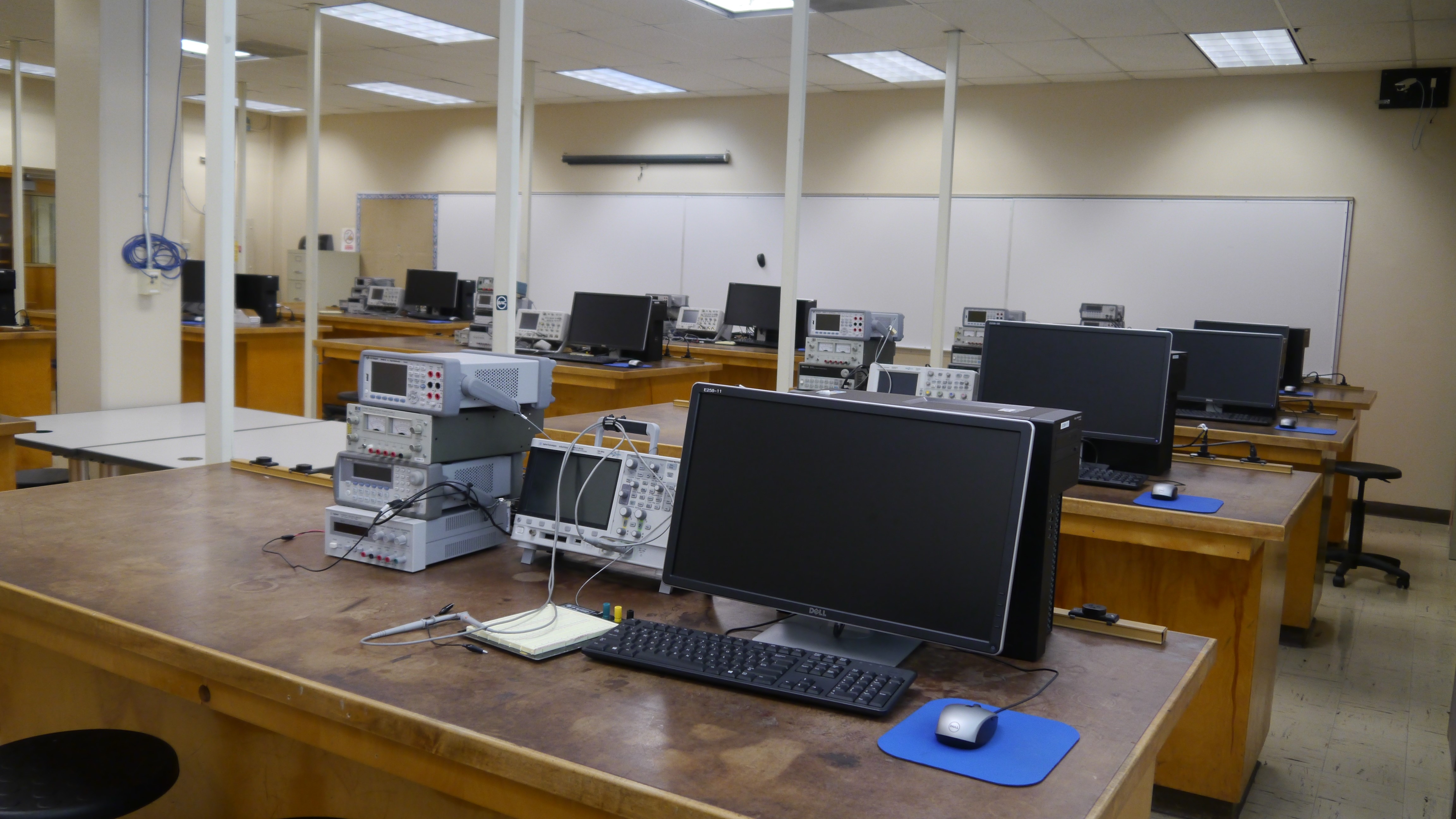 Rows of various wooden desks with computers and electronics equipment