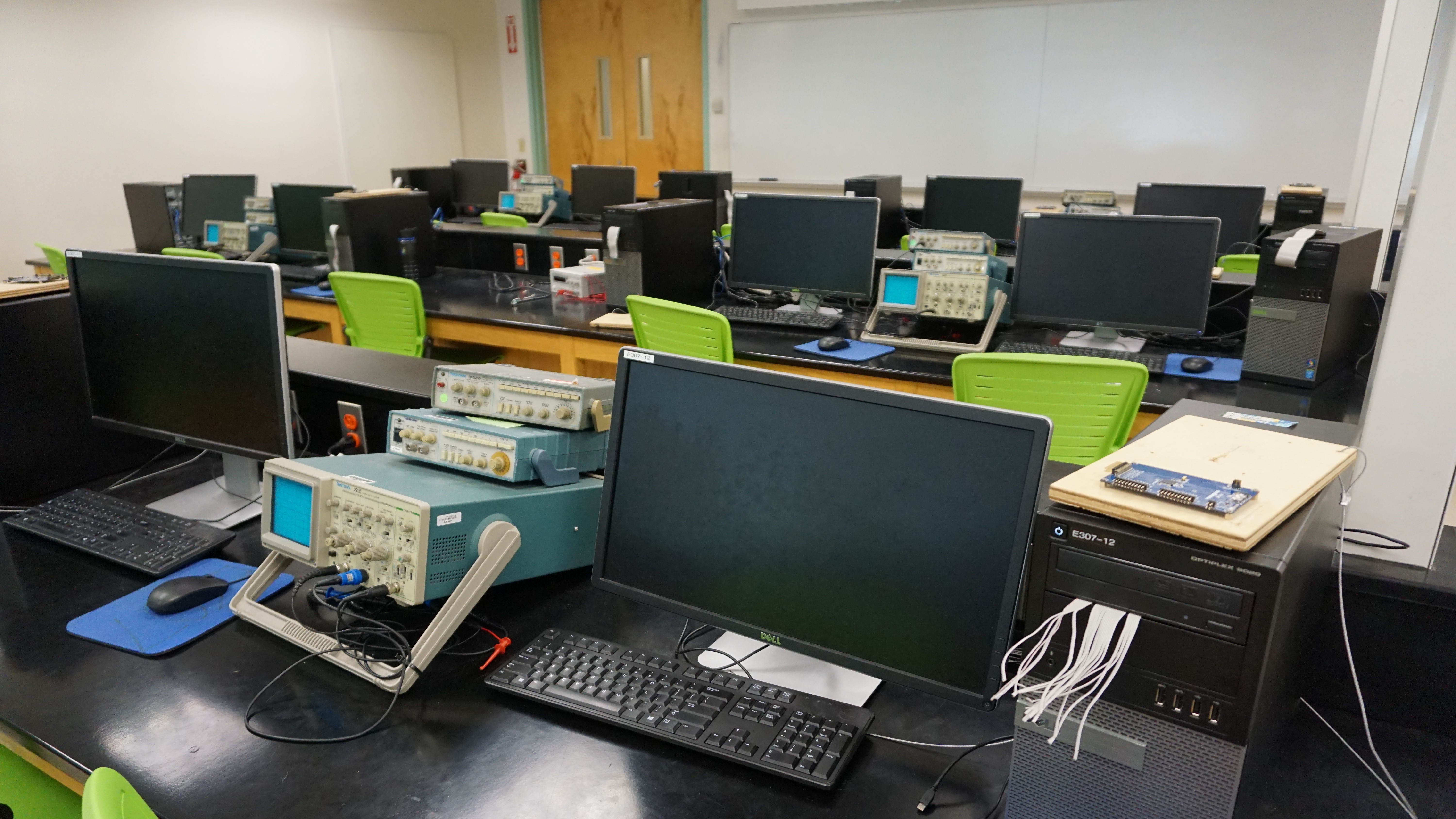 Desks with computers and bright green office chairs.