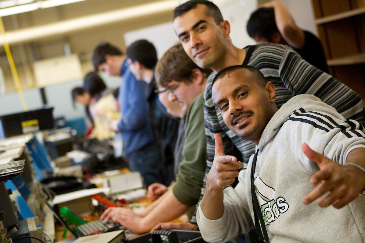 Two students confidently look at the camera while they sit in a full classroom.