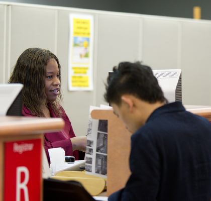 student at registrar window filling out forms.