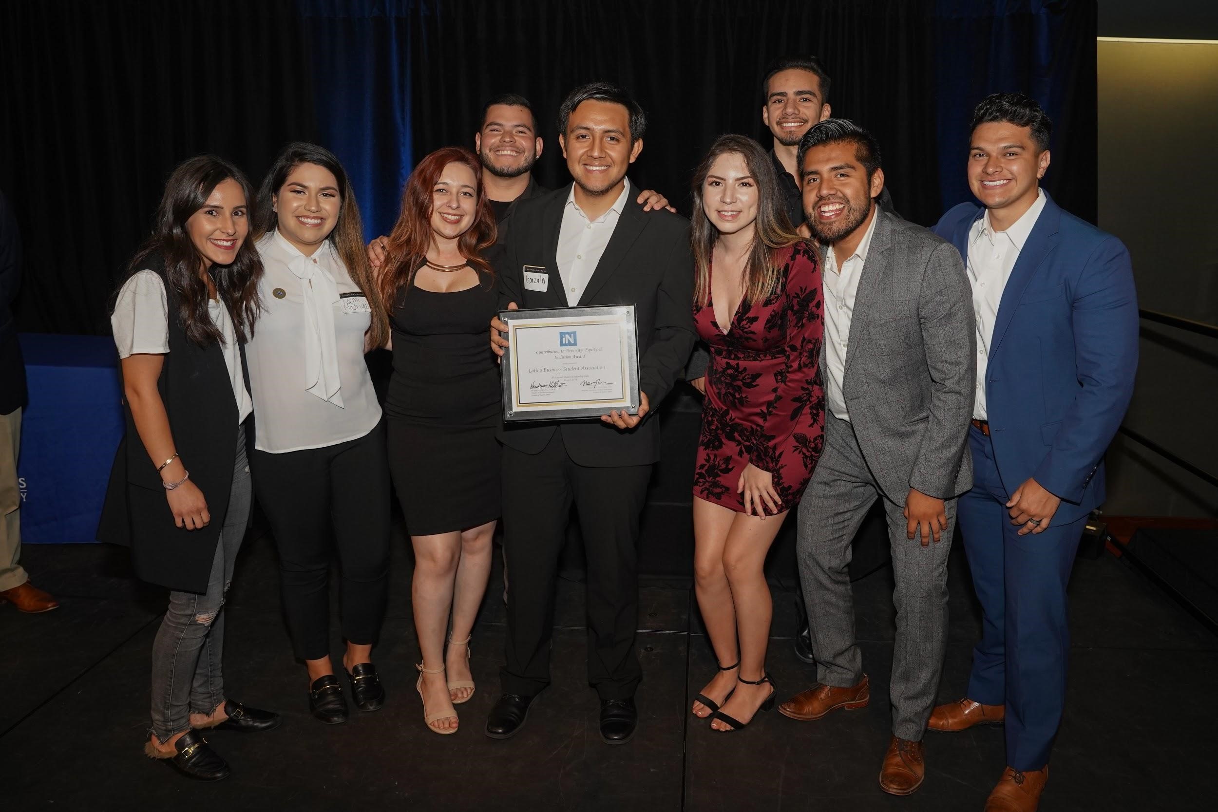 Group of students surrounding young man with certificate