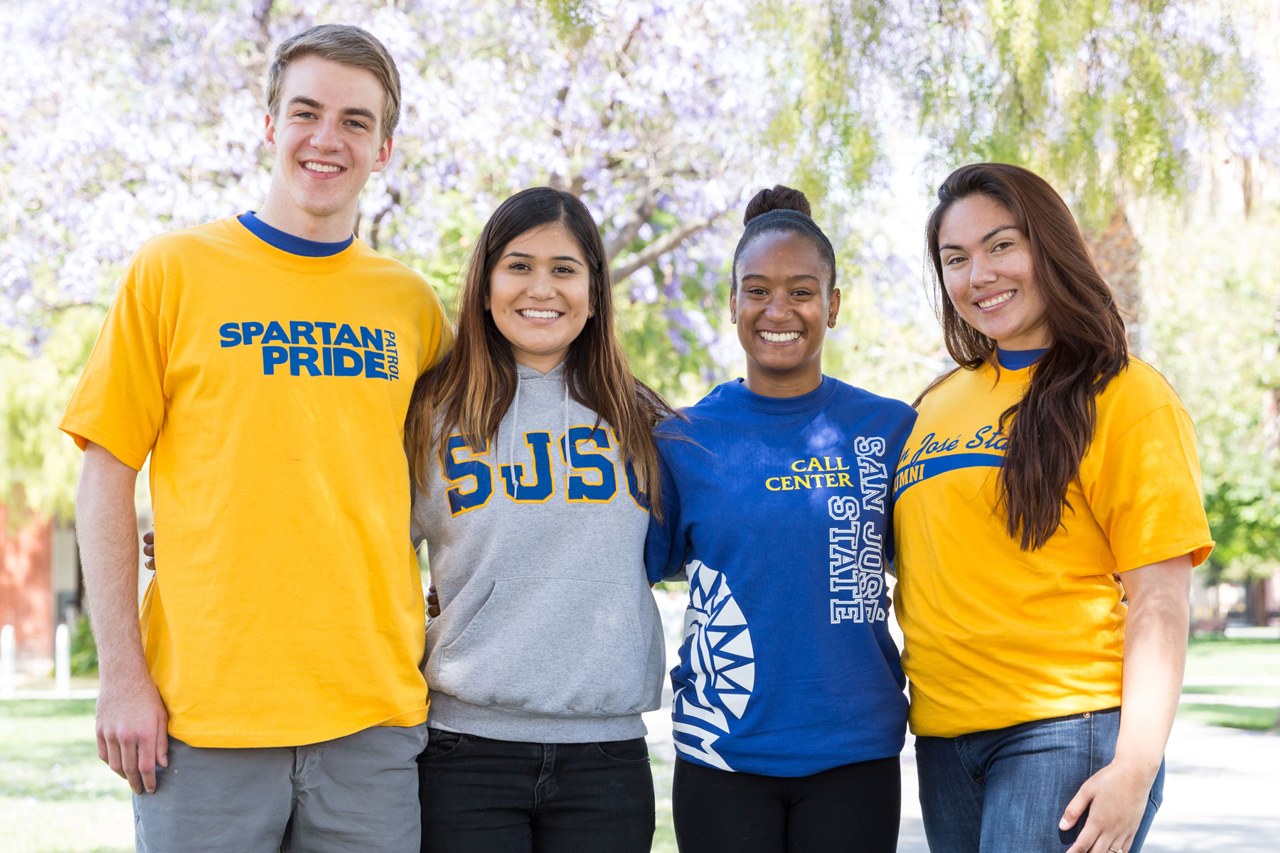 Four diverse students wearing San José State University spartan shirts smile and pose for a photo. 