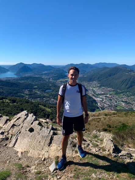 Daniel Renzi, dressed in hiking gear, standing on a mountaintop