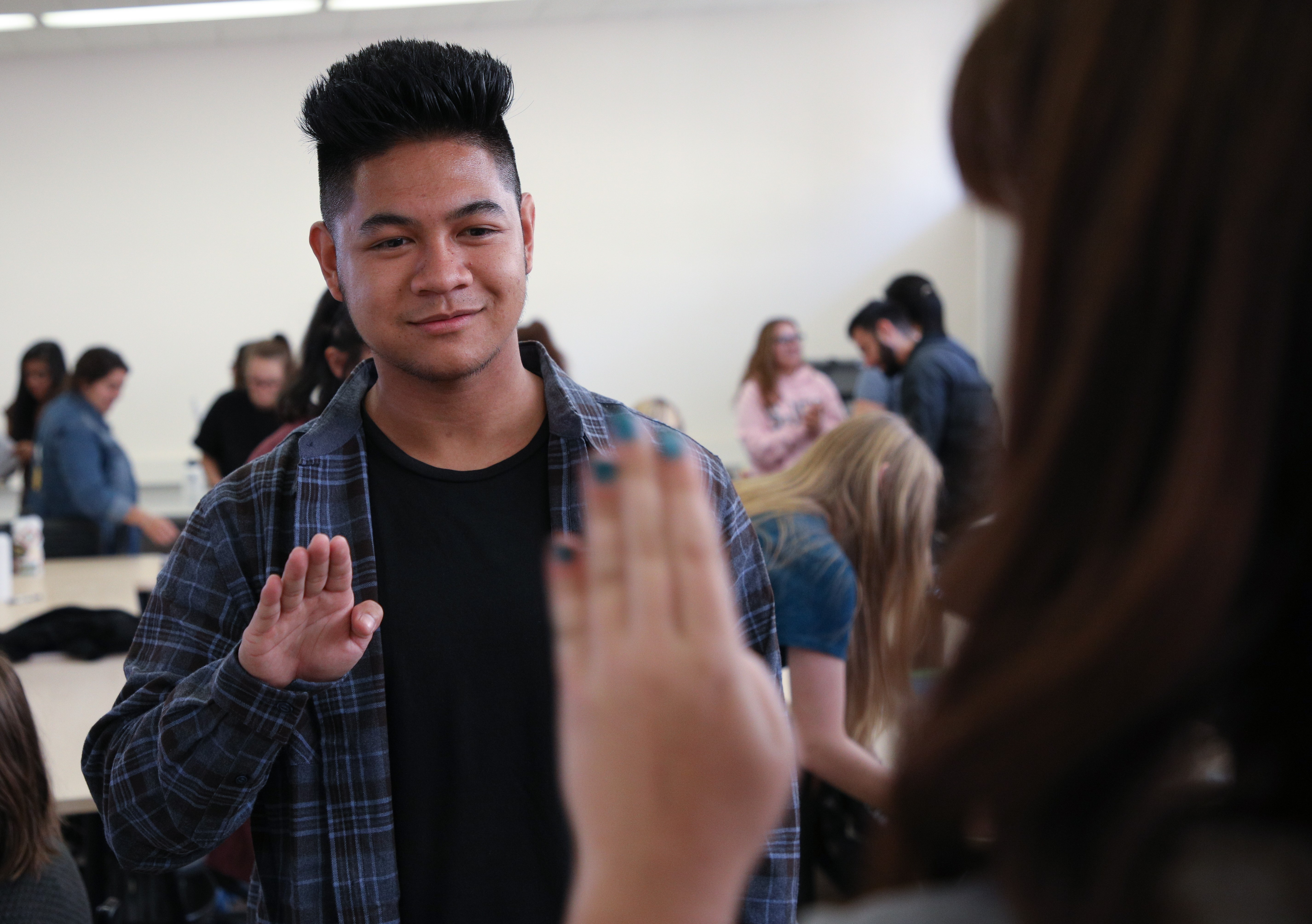 Two students practice using hand signals in a classroom setting.