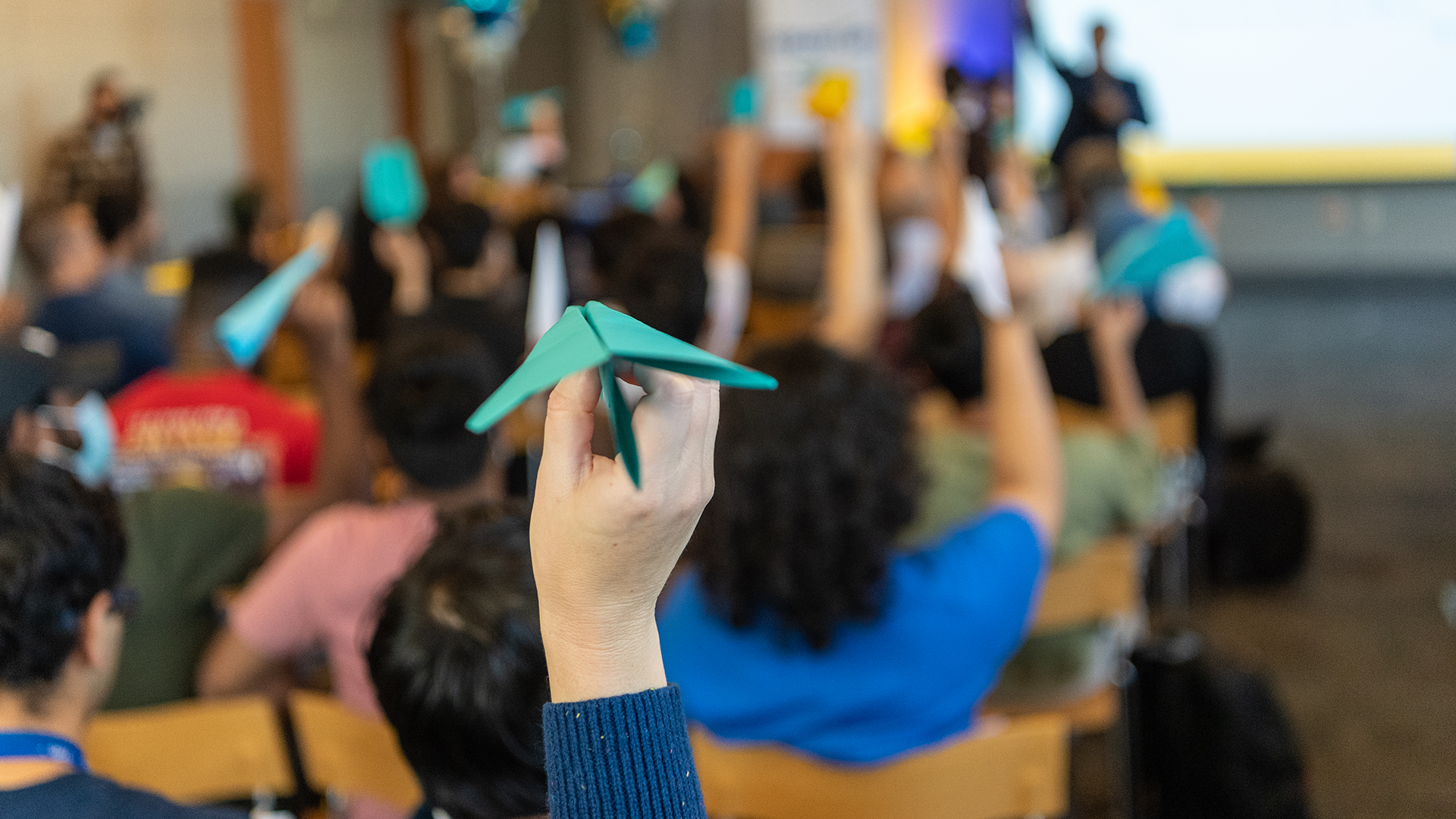 Crowd of people holding up paper airplanes