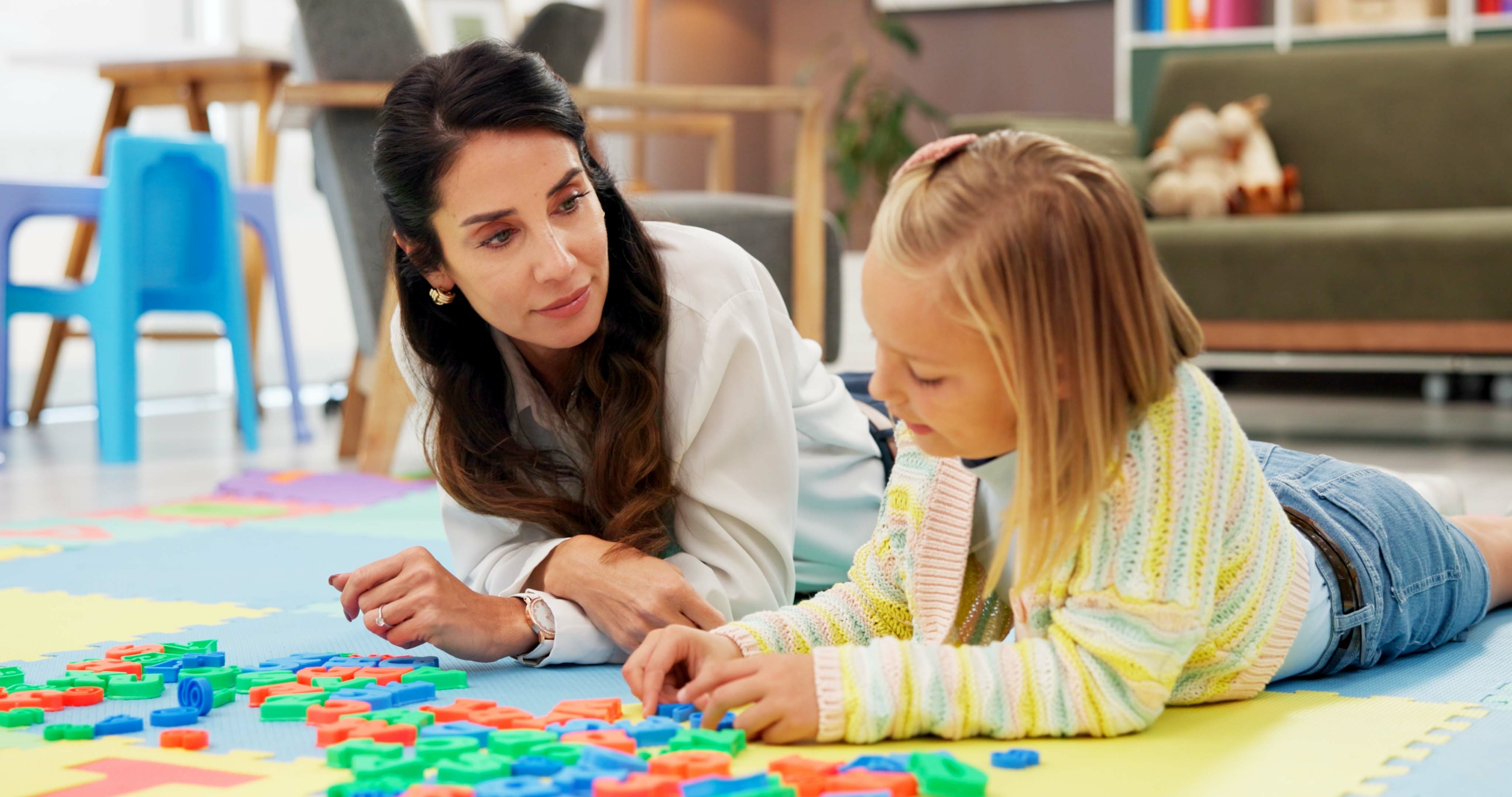 Psychologist studying a child completing an assessment with letters.