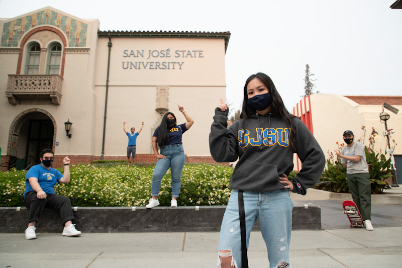 sjsu students pointing to college sign