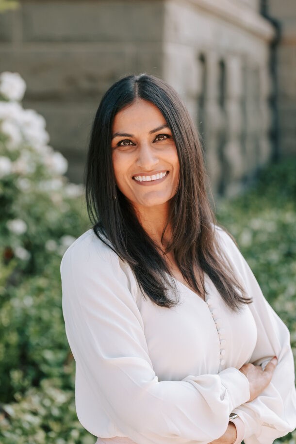 Harpreet "Preet" Samra wearing a white blouse with a background of flowers.