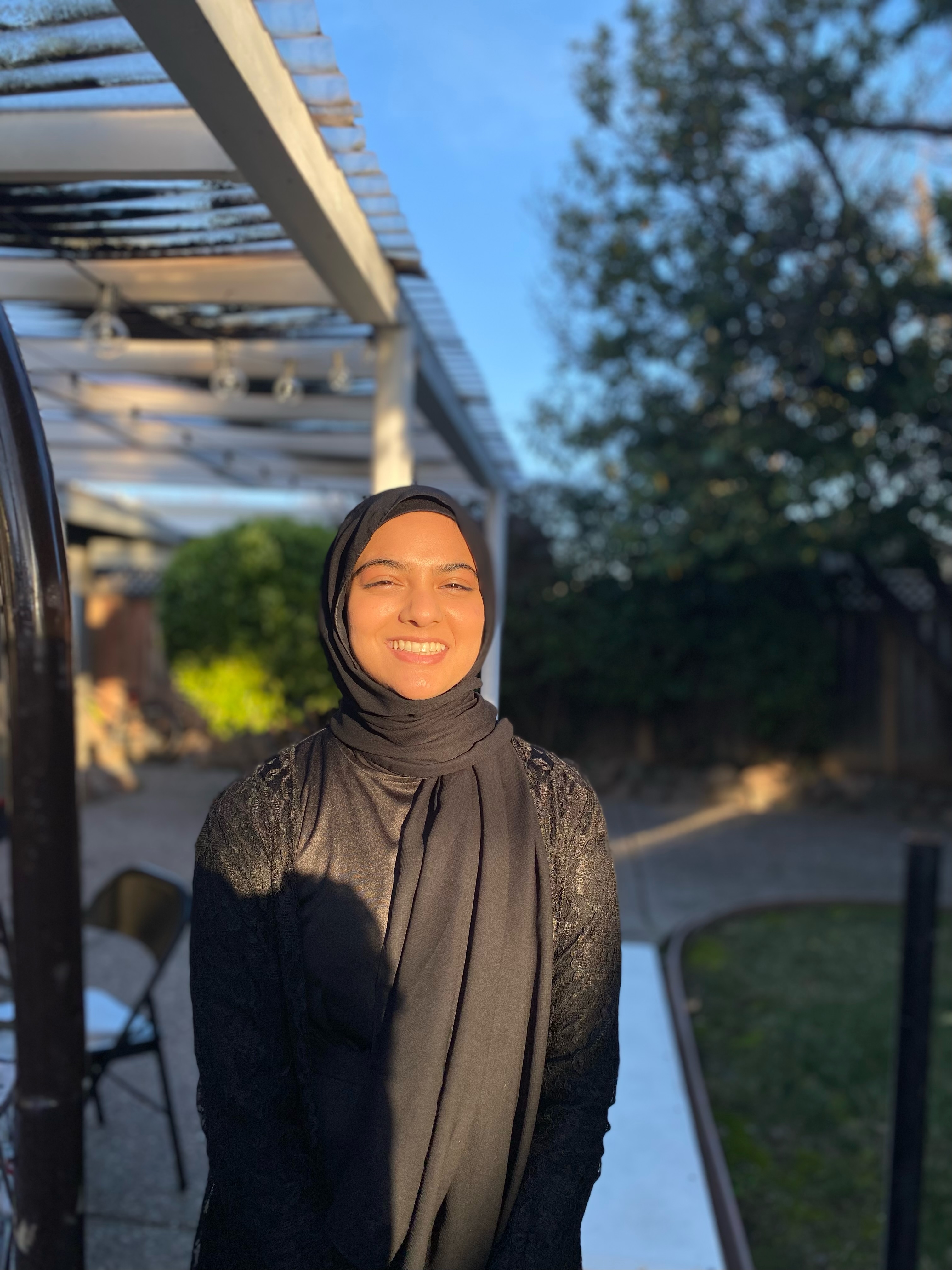 Woman in twenties wearing black headscarf with patio in background