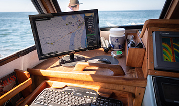 looking out to ocean from boat cockpit, a screen shows tides with numbers