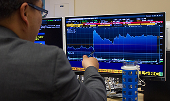 looking over shoulder of person in suit as they point to economic data on screen