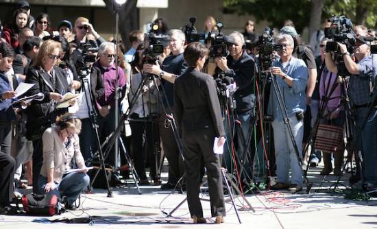 person speaks in front of tons of media people with cameras