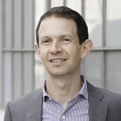 A smiling man with short hair wearing a suit