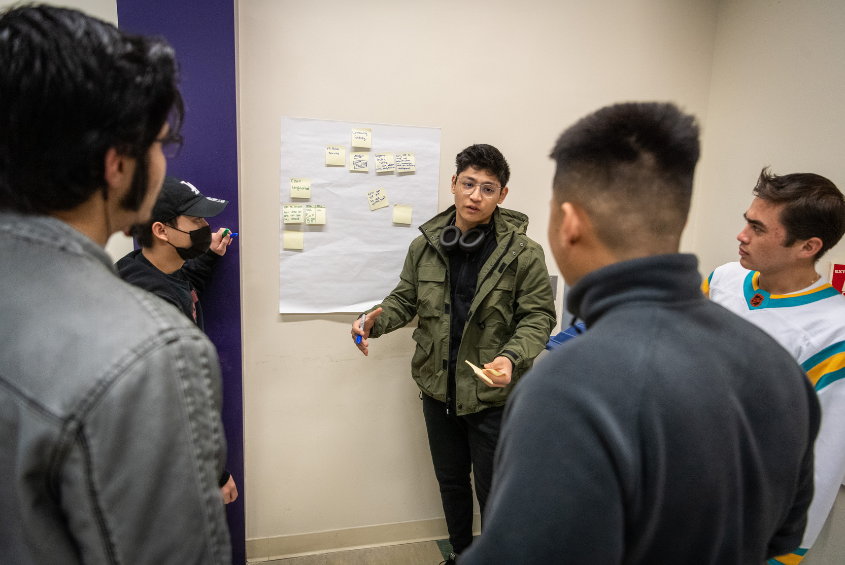 Students around a white board discussing a topic.