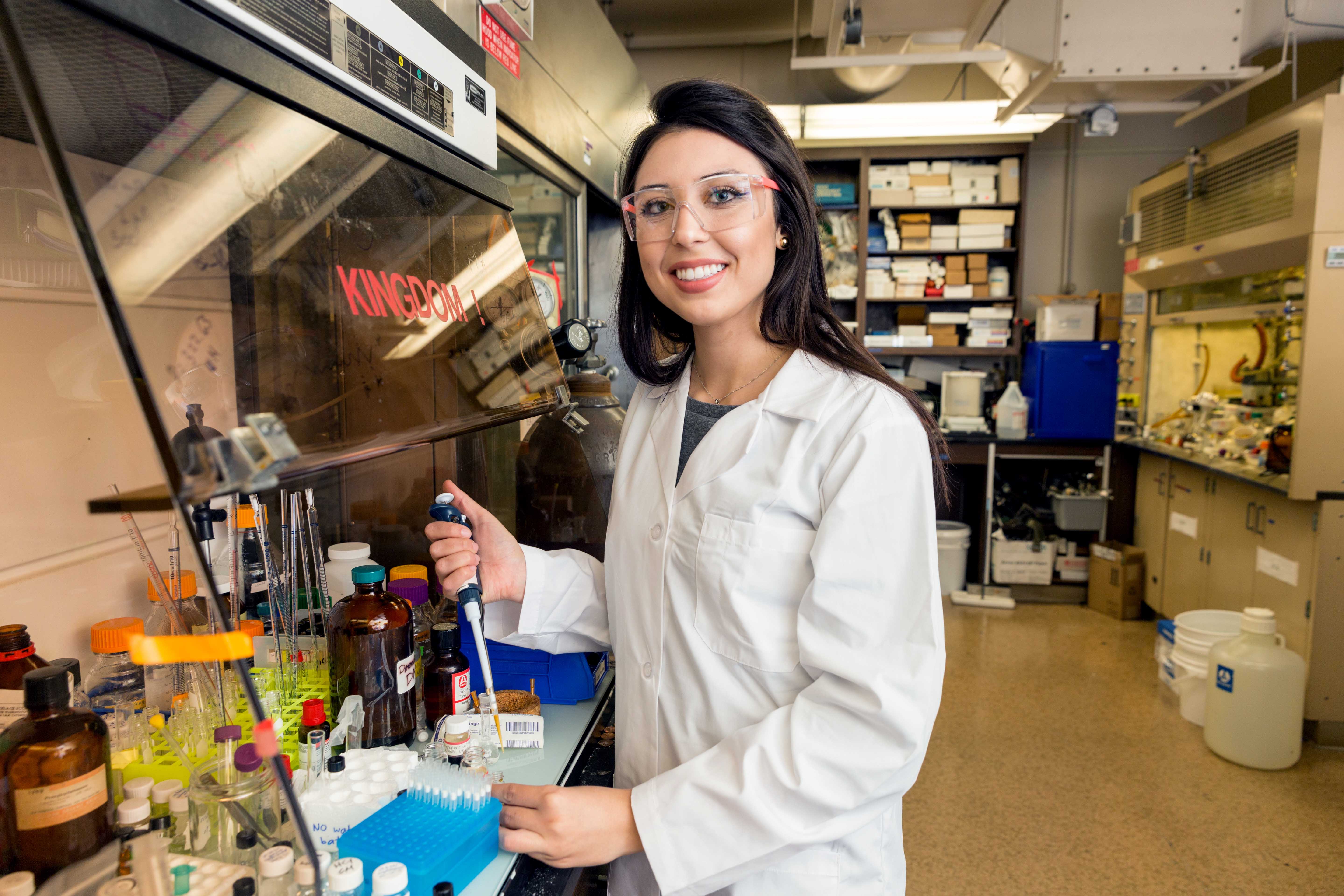 Female chemical engineernig student wearing lab gear and holding lab equipement