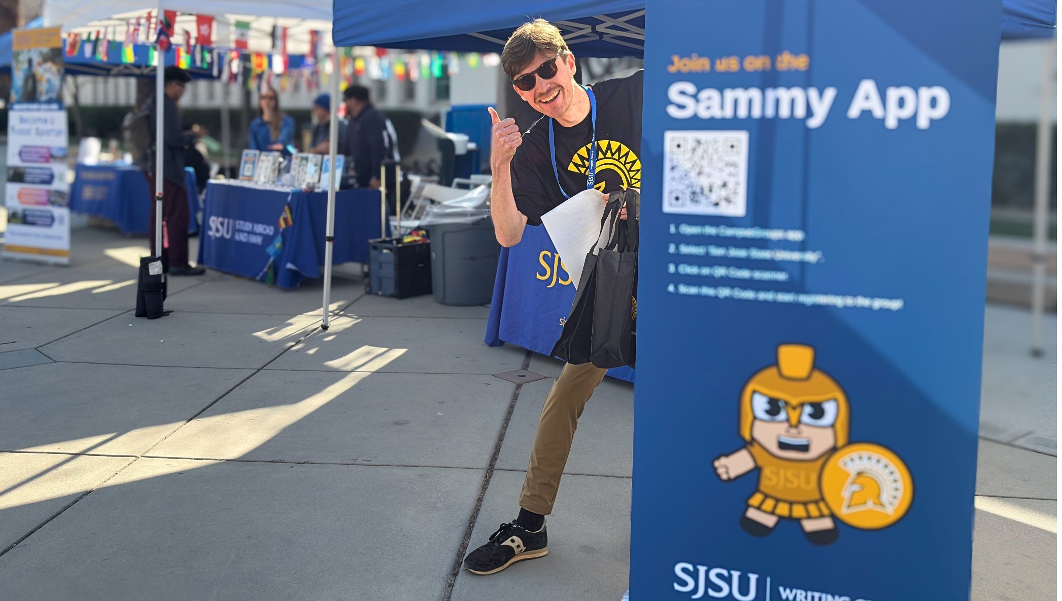 Writing Center tutor with thumbs up standing by banner