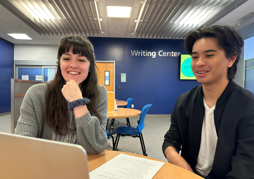 Tutor and student sitting at table looking at a laptop